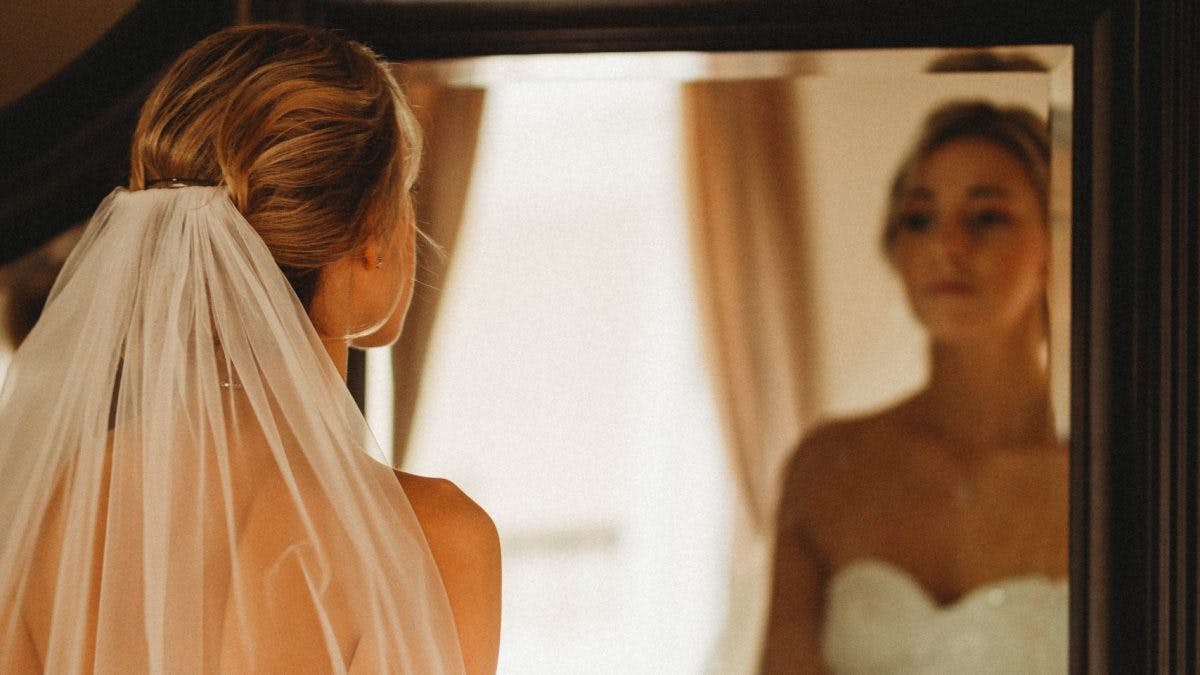 bride is standing in front of a mirror in a wedding dress