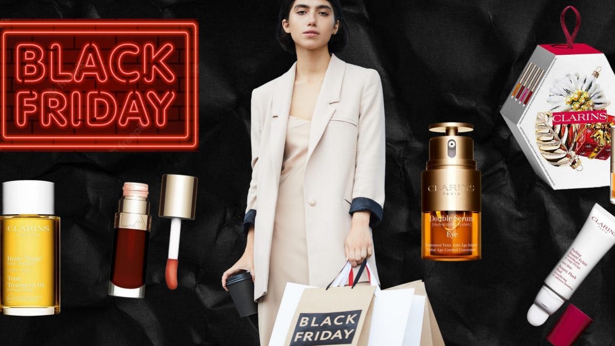 Fashionable lady surrounded by Clarins products holding a Black Friday shopping bag