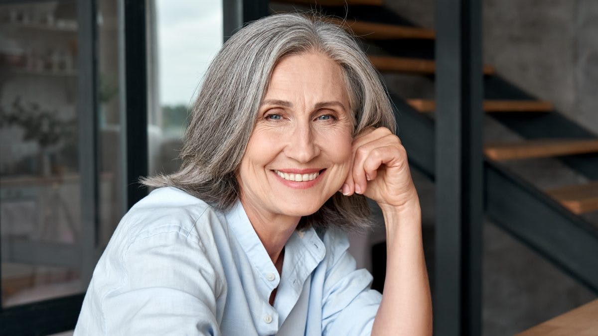 Grey haired lady smiling and relaxed that she has avoidedMenopause Hair Loss