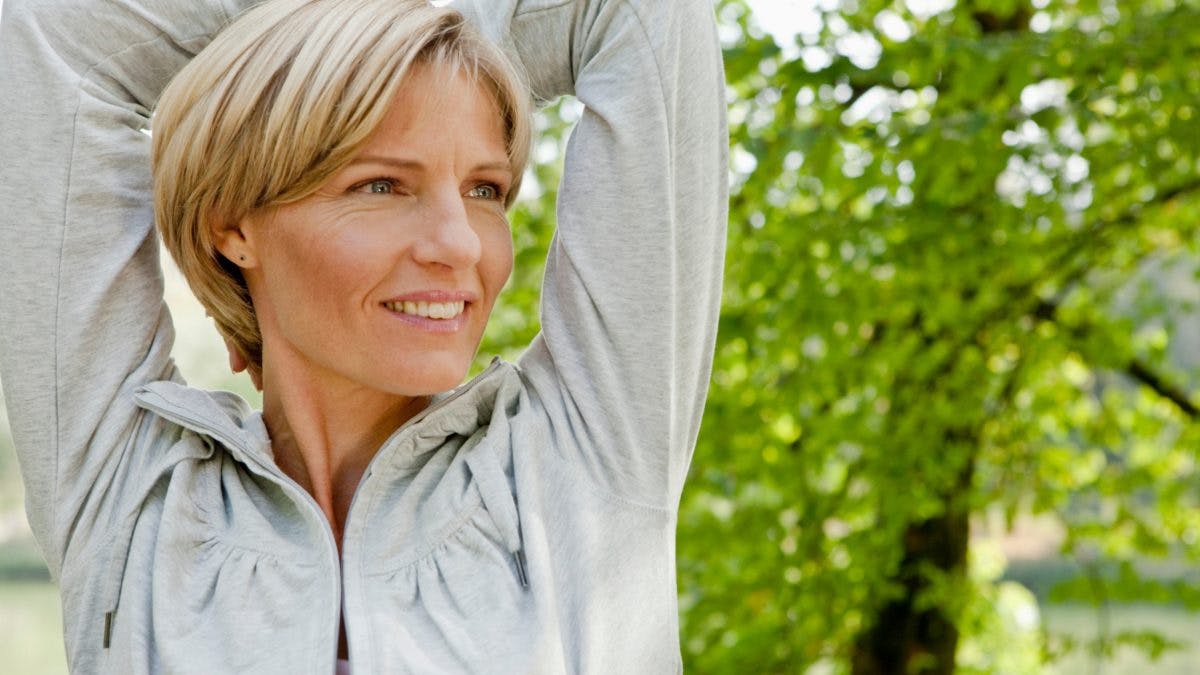 Lady in grey hoodie stretching to relieve Menopause Joint Pain
