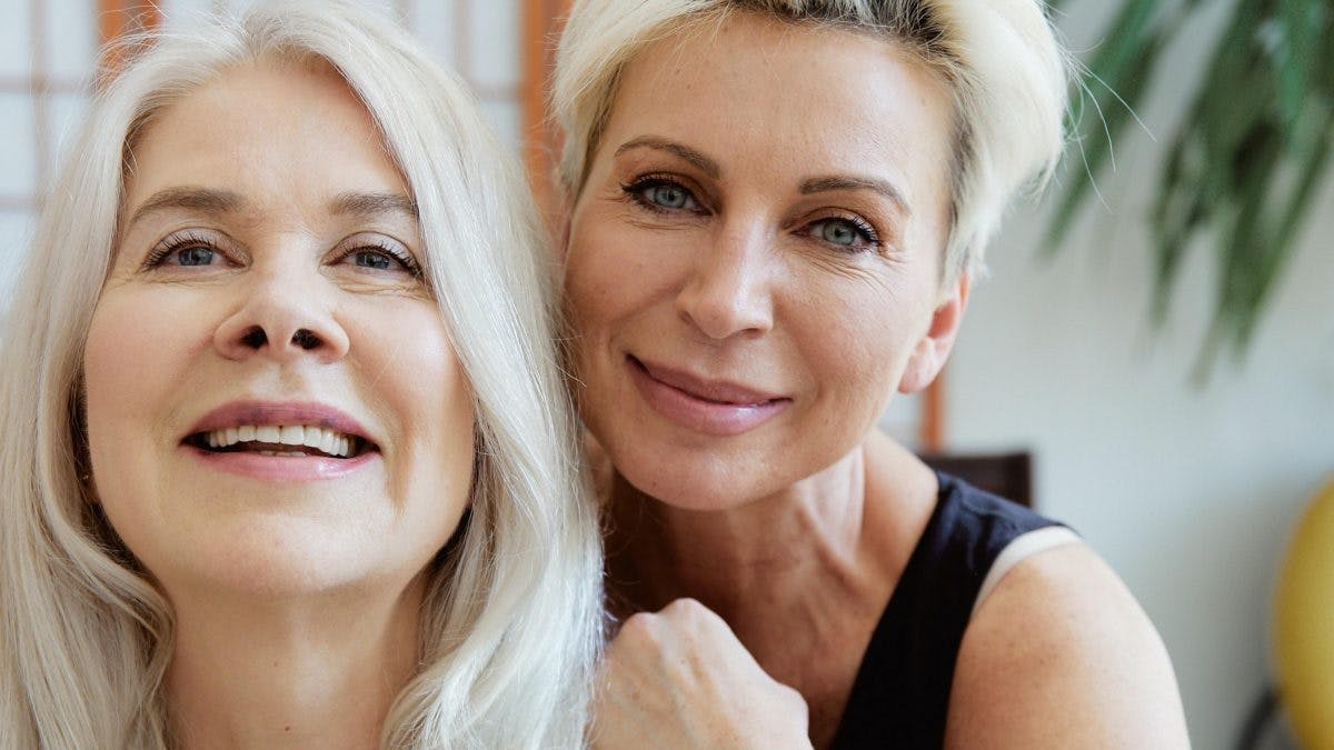 Two woman smiling; unphased by post menopausal symptoms
