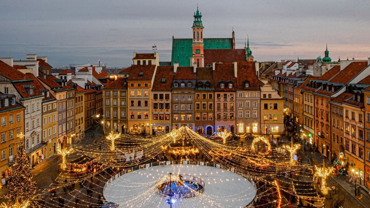 One of the best Christmas markets in a town square with large christmas treee in bottom left and a circular ice rink in the centre that's decorated with many lights