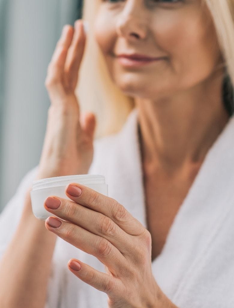 Mature woman applying anti-ageing skin care