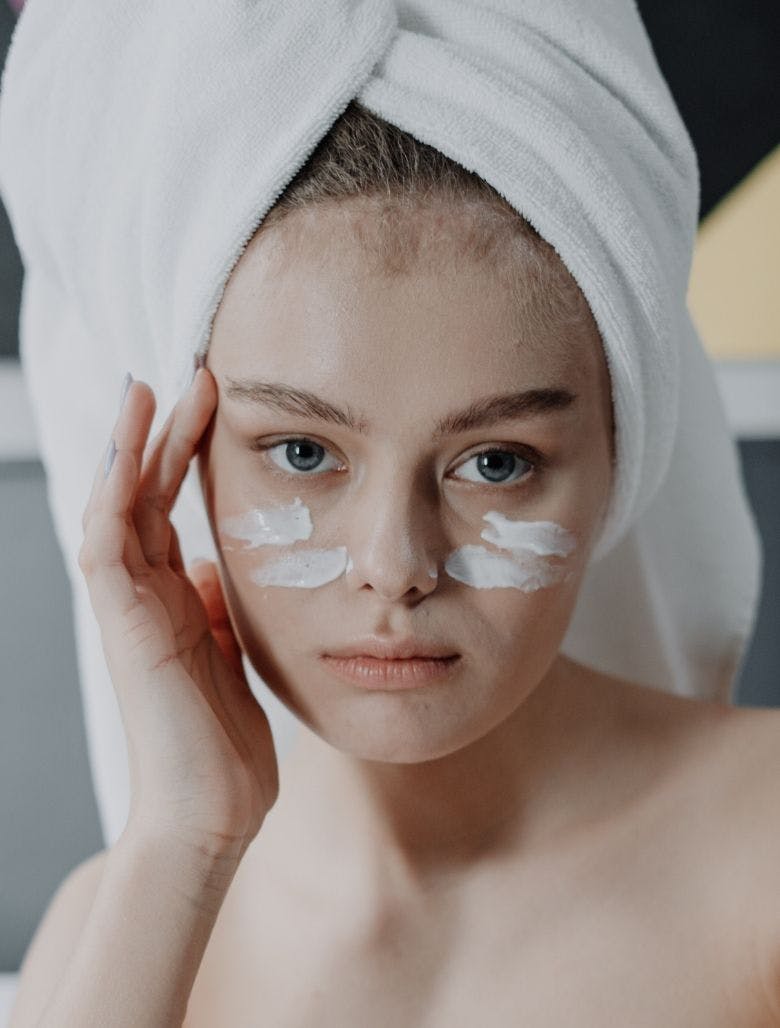 Woman wearing hair towel applying product to her face