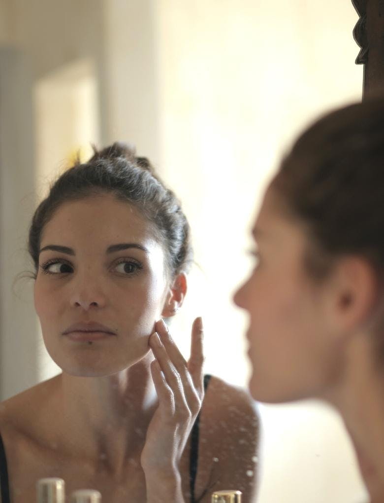 woman checking her face in the mirror