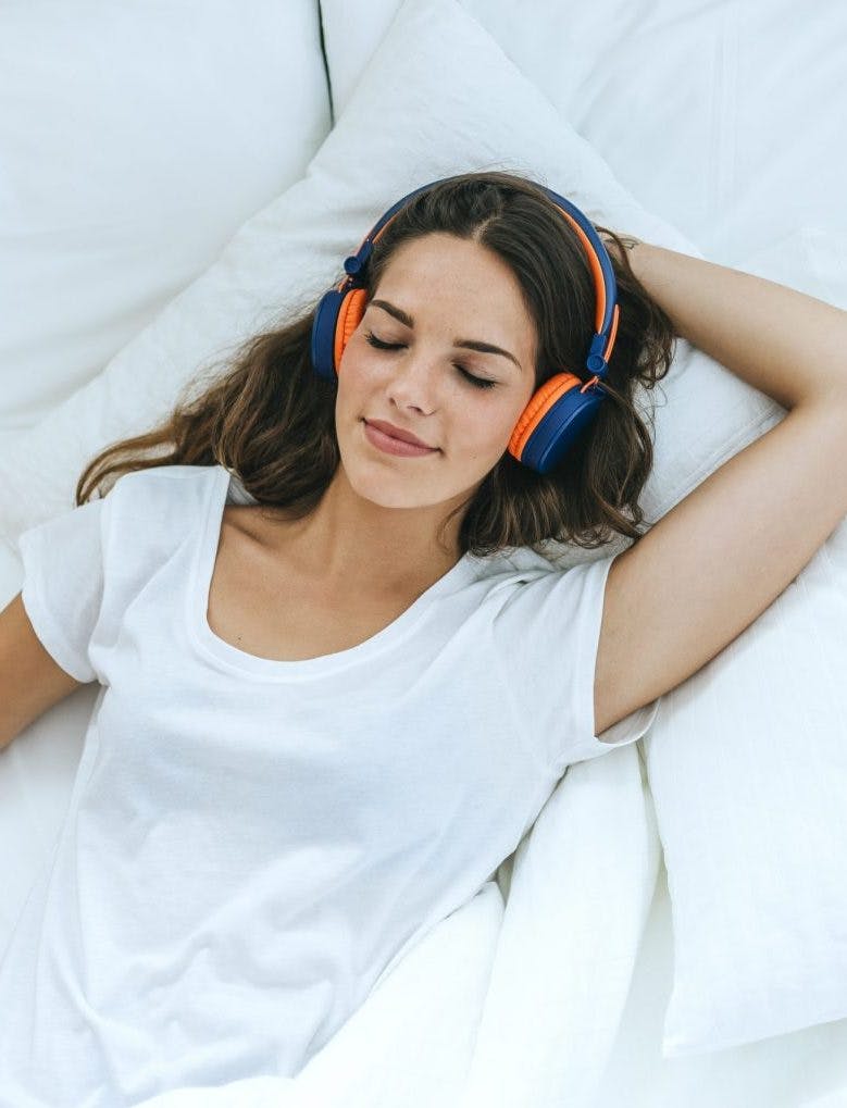 woman laying in bed listening podcast for sleep