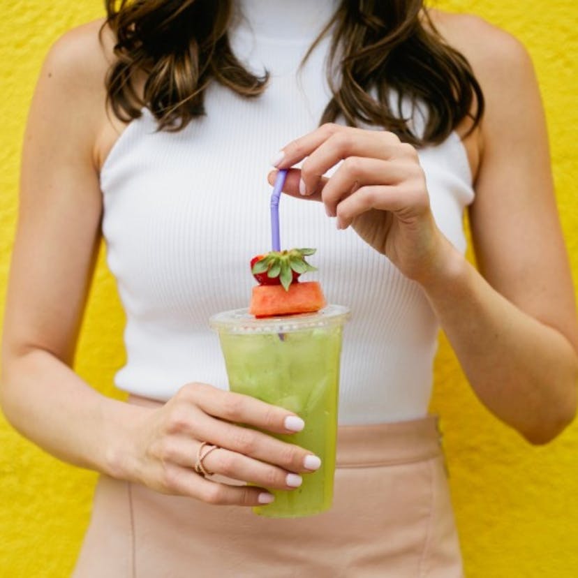 woman holding green juice 