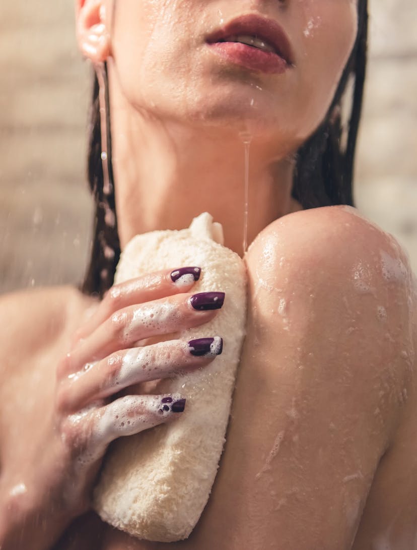 woman exfoliating her body in the shower