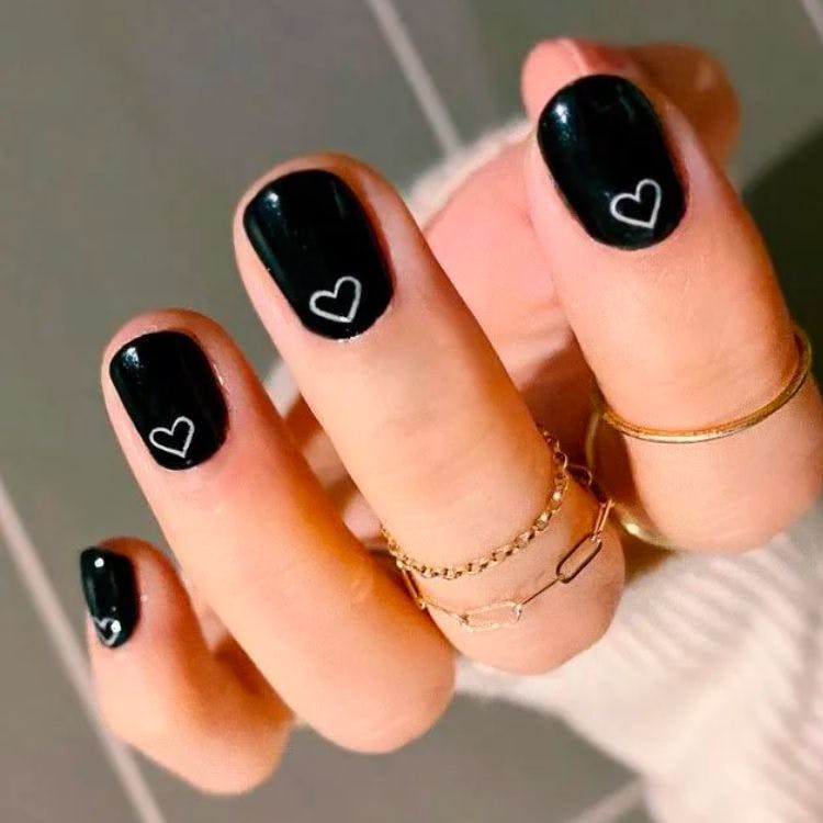 Black nail polish with white hearts nail art